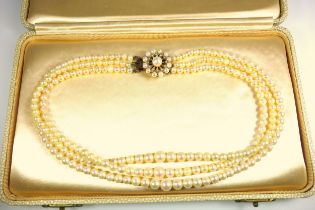 Triple row graduated cultured pearl necklace, L.39.5cm, with a 9ct gold pearl set floral clasp, L.