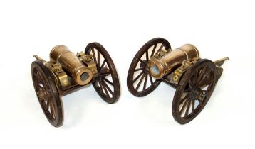 Pair of brass models of cannon, each mounted on a carriage with brass rimmed wood wheels, L.34.5cm