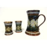 Royal Doulton Lambeth stoneware ale jug and two beakers, circa 1920, each with white metal rims, the