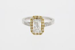 Stamped 18K and partial hallmark. An emerald cut diamond ring with a halo of yellow diamonds.