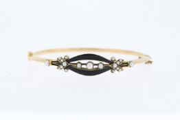 Tests 15ct Victorian enamel and pearl bangle, hinged with a safety chain.