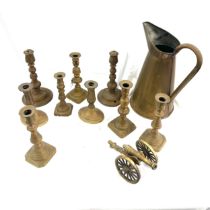 Selection of antique and later brass candle sticks and a large water jug, canon ornament