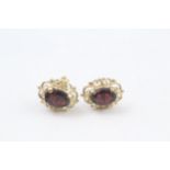 9ct gold oval cut garnet stud earrings with a scroll patterned border (1.7g)