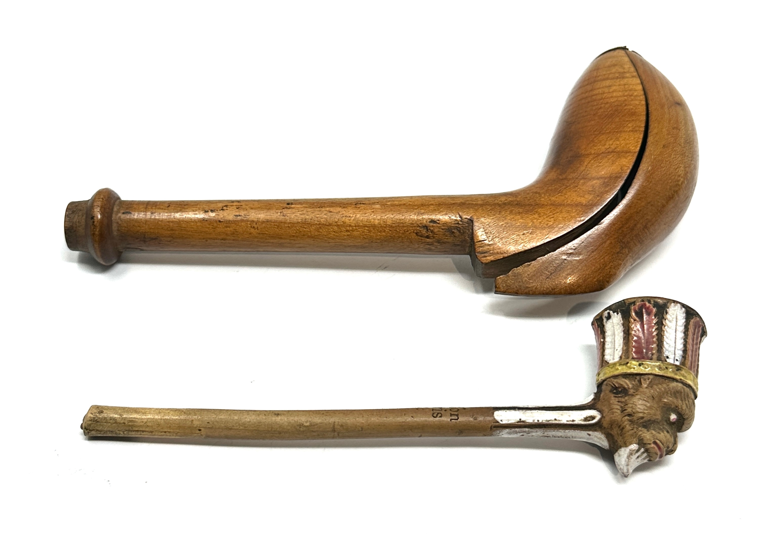 An 18thC carved fruit wood pipe case opening to reveal a clay pipe having glazed indian head