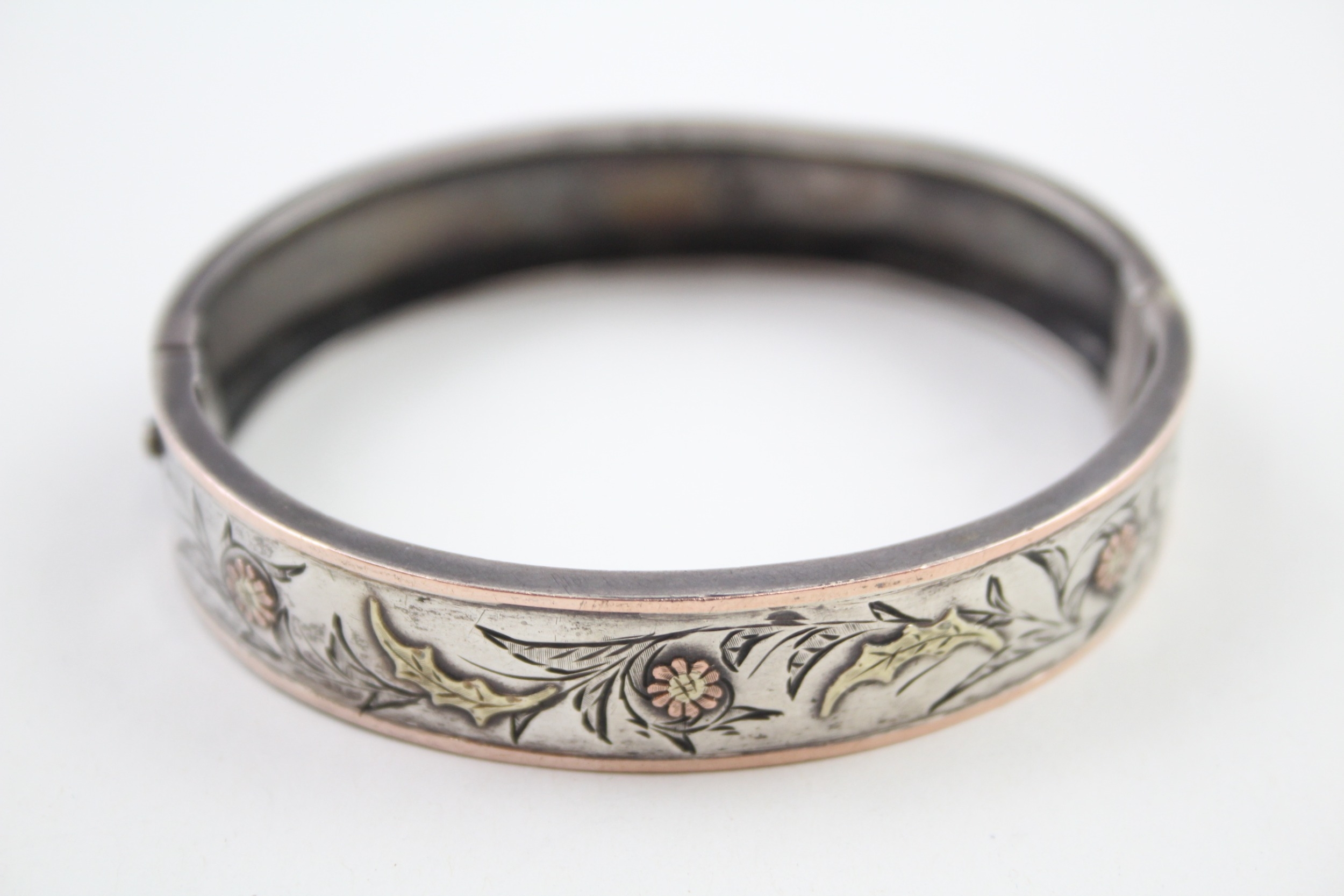 A decorative Victorian silver bangle with gold floral detailing (16g)
