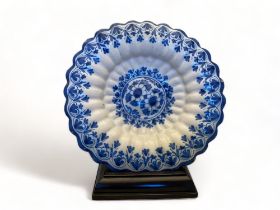 A 19th century Dutch delft blue and white floral glazed dish with a mahogany plate stand