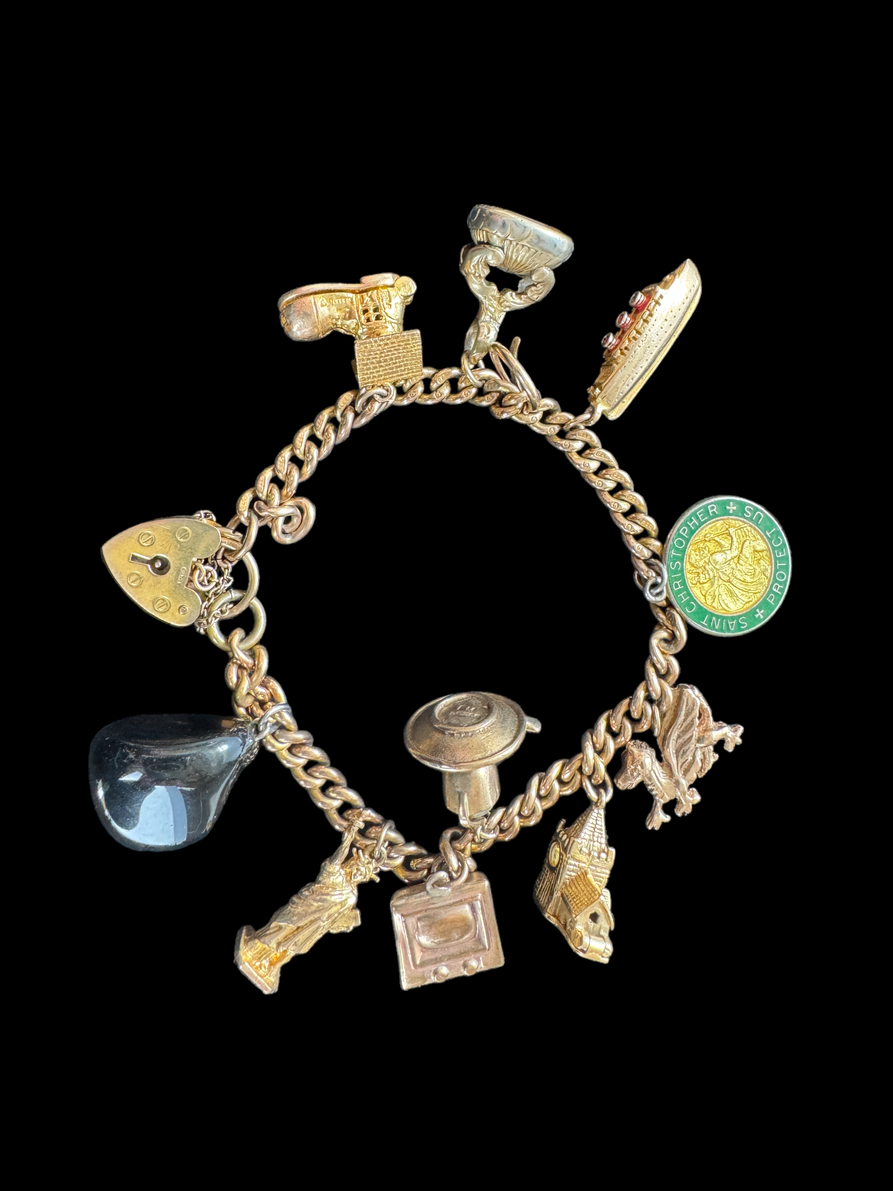 A 9ct gold curblink bracelet with 9ct gold heart padlock clasp and hung with ten charms, 1960s