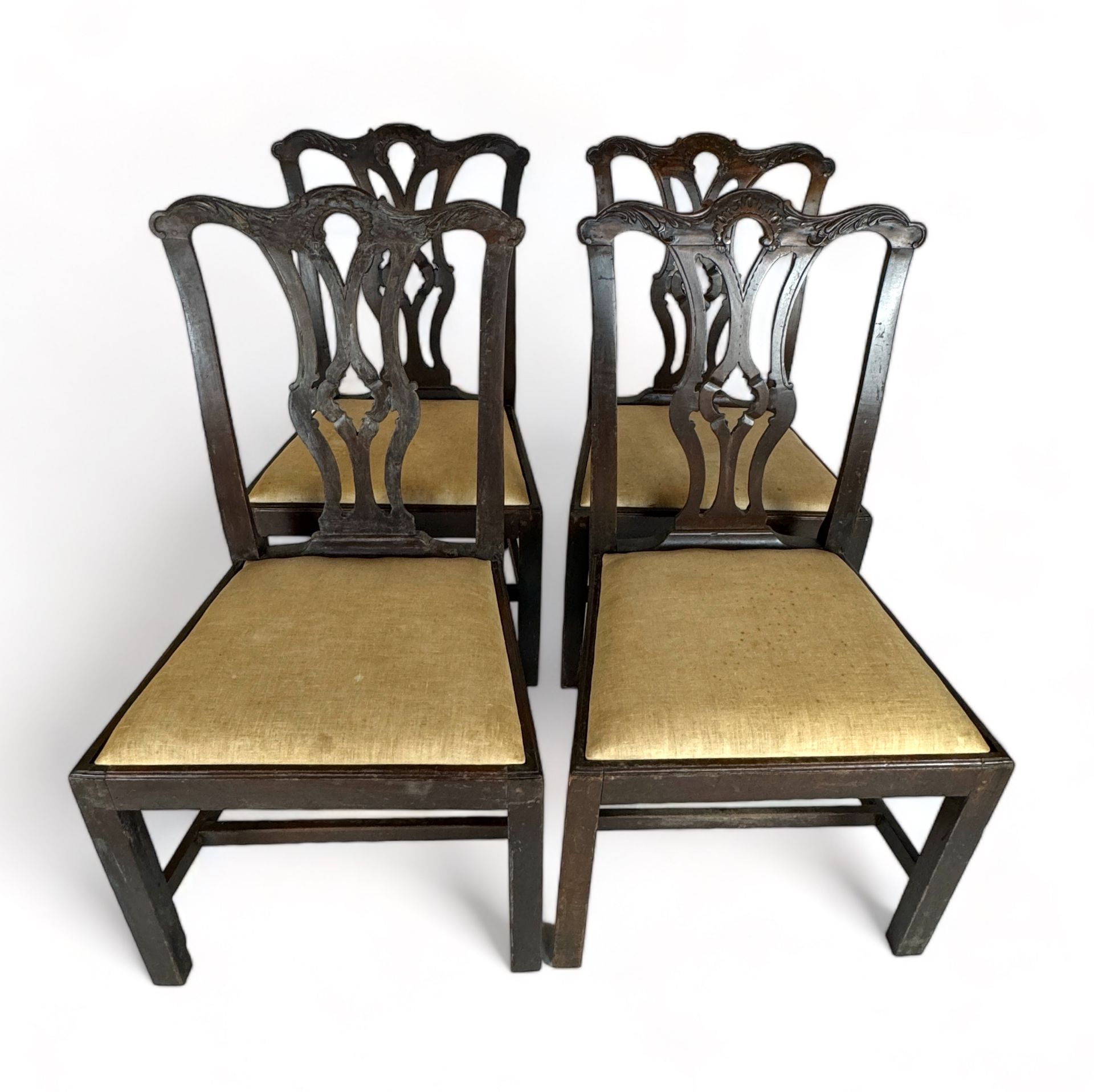A set of four George III provincial carved mahogany dining chairs in the Chippendale style