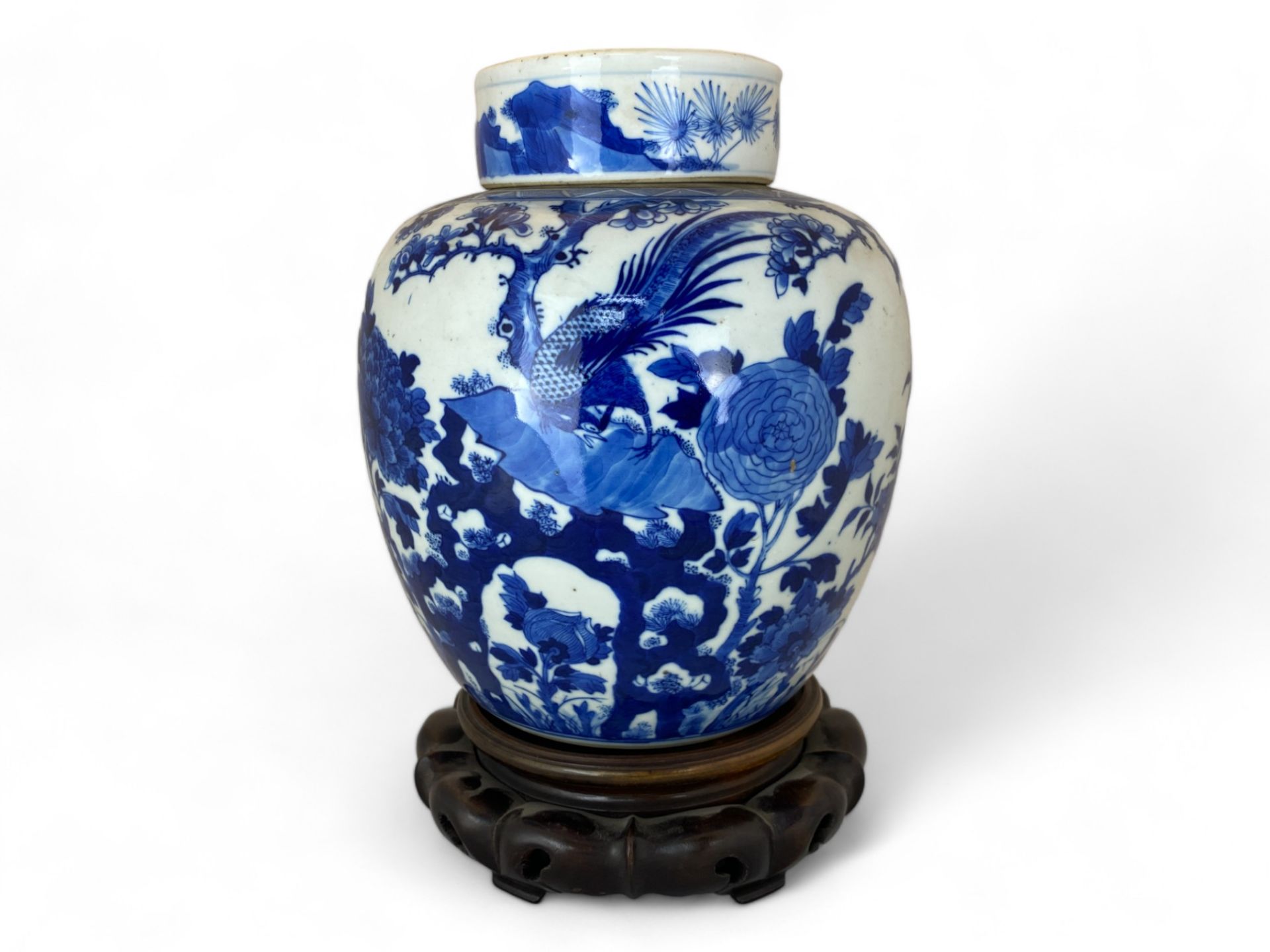 A Chinese blue and white ginger jar and lid on a pierced hardwood stand