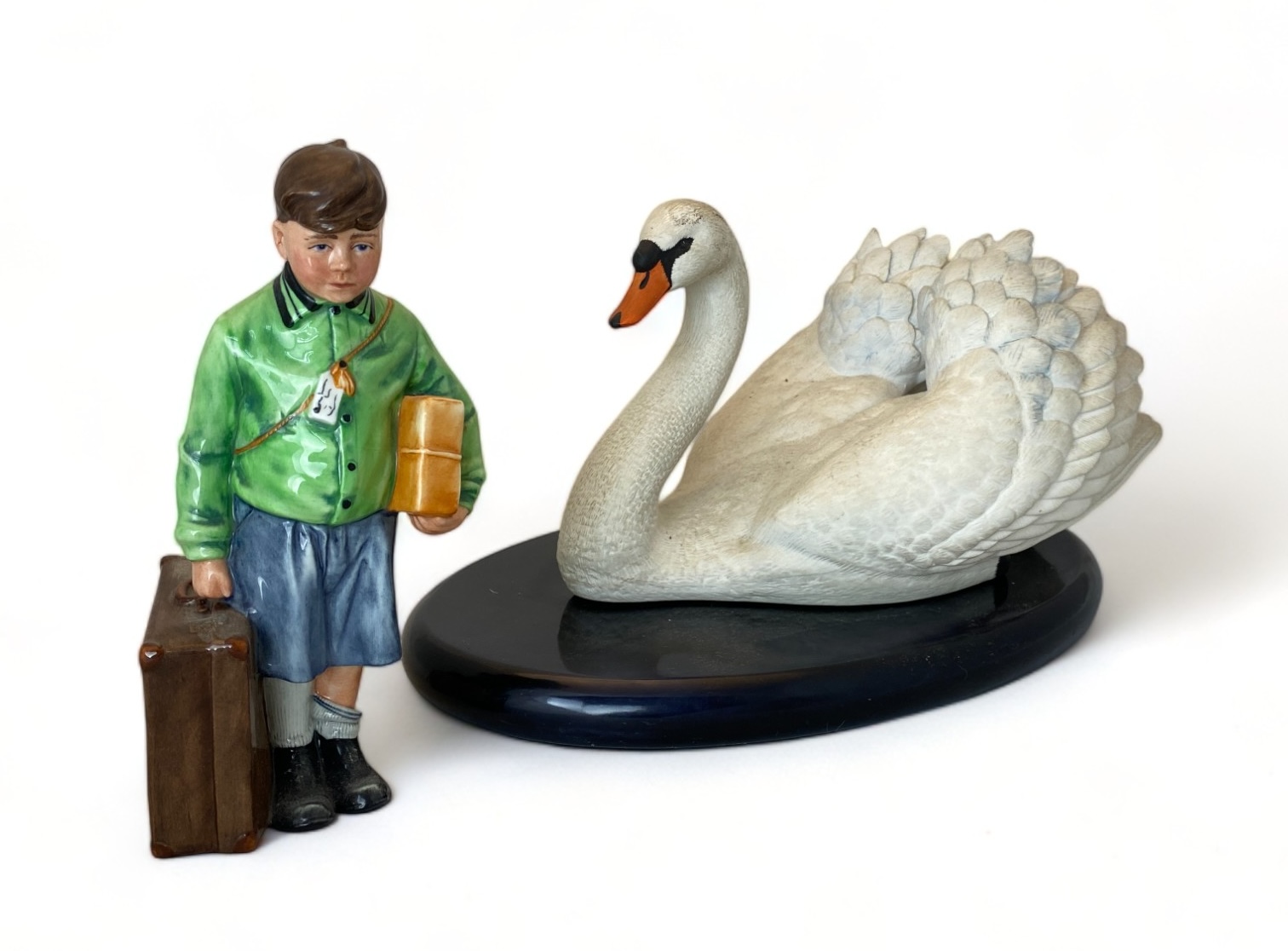 A Royal Doulton porcelain figure, 'The Boy Evacuee' and a Franklin Mint bisque porcelain 'Royal Swan