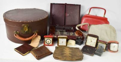 A group of vintage travel alarm clocks, a red leather clad vanity case with the fitted contents, a