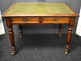 A Victorian oak writing desk with green leather top, turned legs raised on castors, 76cm high by