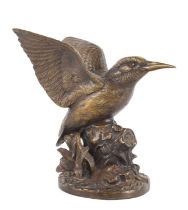 A bronze sculpture of a Kingfisher with wings outstretched perched upon a naturalistic tree stump,