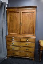 A Georgian oak cabinet on chest, the upper portion with moulded cornice over a pair of panelled