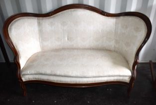 A Victorian mahogany framed sofa, serpentine shaped back, upholstered in a cream floral fabric,