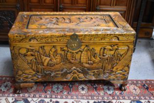 A large mid 20th century Chinese blanket chest or coffer, deeply carved with ships and fish, with