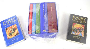 A set of Harry Potter Deluxe edition books, the first five volumes bound in coloured fabric and