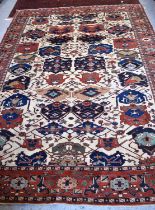 A large rug, possibly Afghan, the cream central ground decorated with repeated geometric motif,