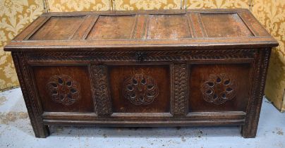 A 17th century oak coffer with four panel lid and three panel front, later carved with rosettes to