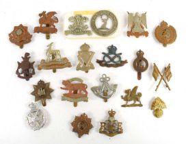 A collection of military cap badges to include Devonshire Regiment, Lovat's Scouts, Earl of