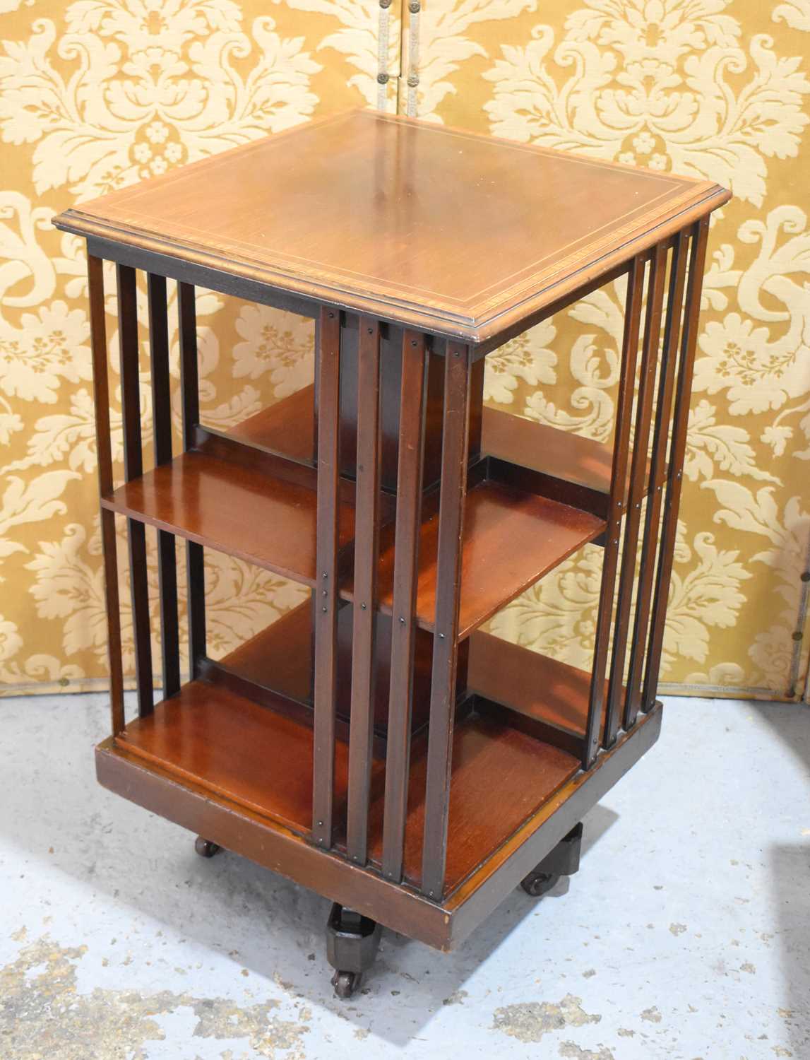 An Edwardian mahogany revolving bookcase, the top with satin wood inlaid border.