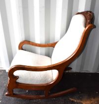 A Victorian mahogany framed rocking chair, carved back, with cream upholstery.