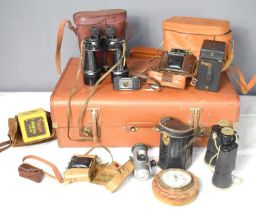 A group of vintage cameras and binoculars inside a vintage suitcase to include an Ensign Midget.