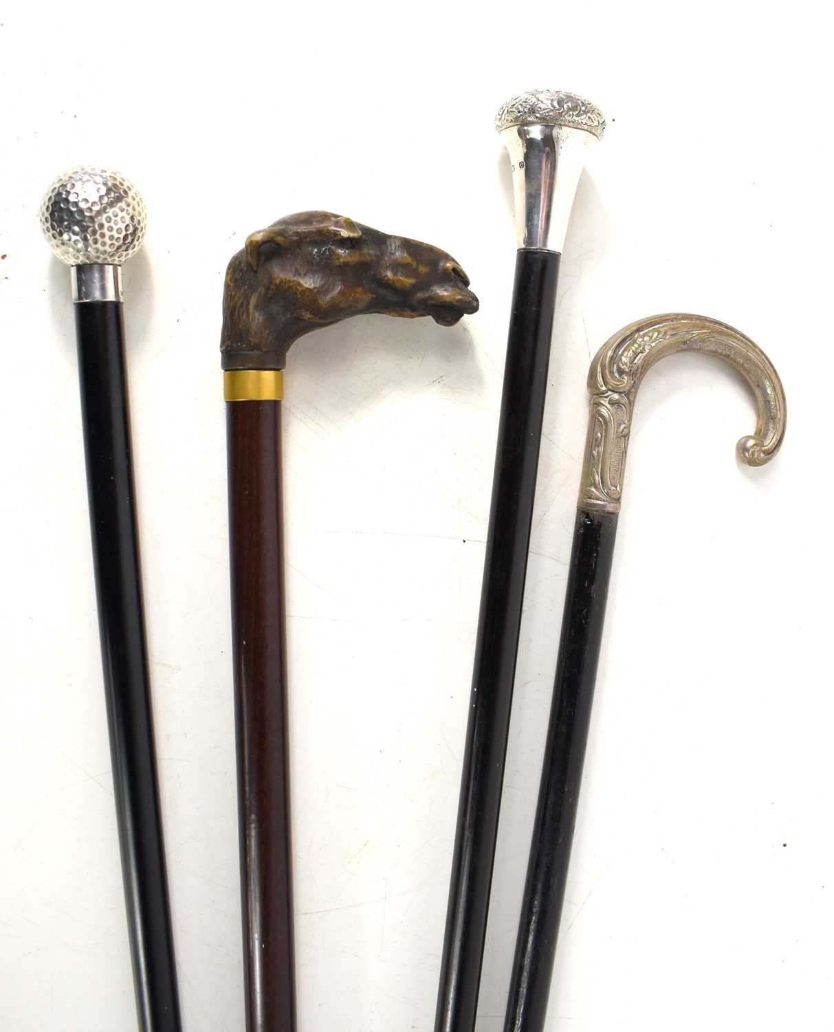 A group of vintage walking canes, two having silver handles, the other having a handle in the form