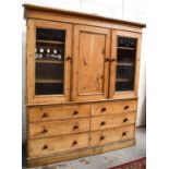 An antique pine Housekeepers’ cupboard, the central door flanked by two glazed cupboard doors