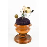 A 19th century treen pin cushion stand, with various hat pins, the turned pedestal stand housing the