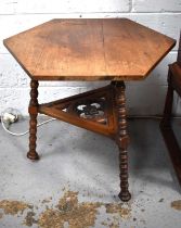 A Hexagonal mahogany Arts & Crafts side table, with cope castors, and three legs.