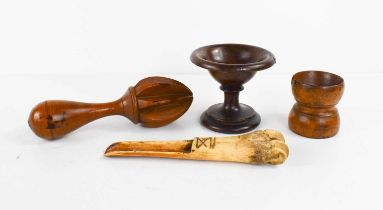 A 19th century treen lemon squeezer, and a bone carved apple corer, a lignum vitae pedestal salt,