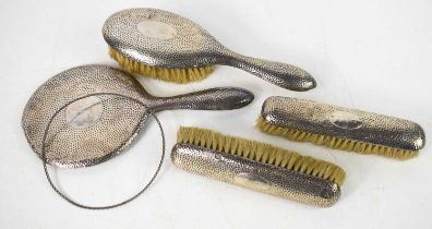 A silver repousse dressing table set, comprising clothes brushes, hair brush, and hand mirror. A/F.