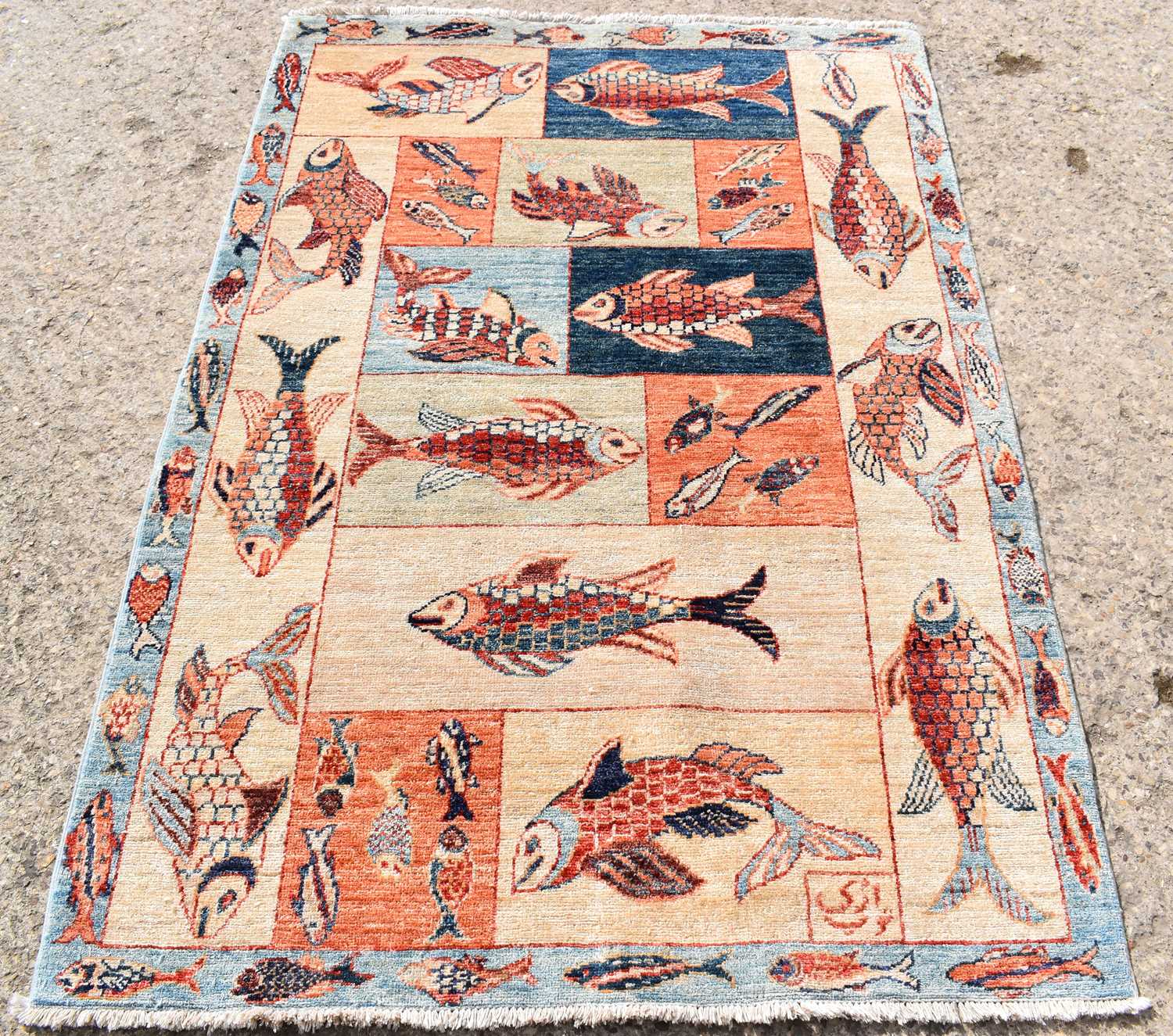 An Afghan wool rug, depicting various fishes on a cream ground, 121 by 178cm.