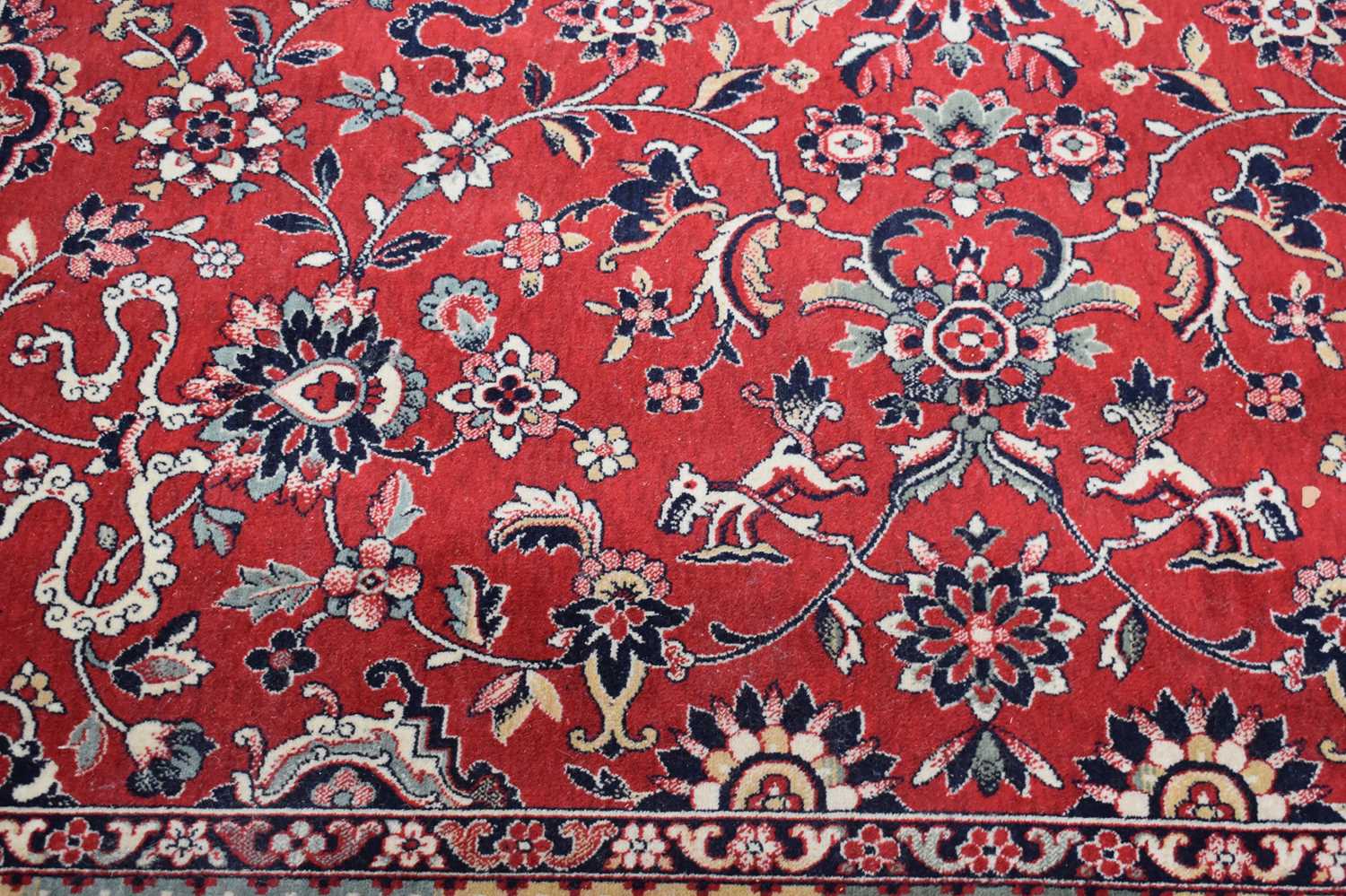 A large Middle Eastern wool rug with red ground, the centre decorated with stylised flowers with - Image 2 of 3