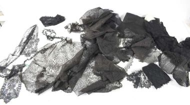 A collection of assorted black mourning lace to include a face covering, offcuts, borders and