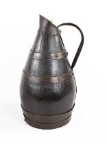 An 18th century bog oak coopered pitcher, bound in iron strap work, handle and spout, 31cm high.