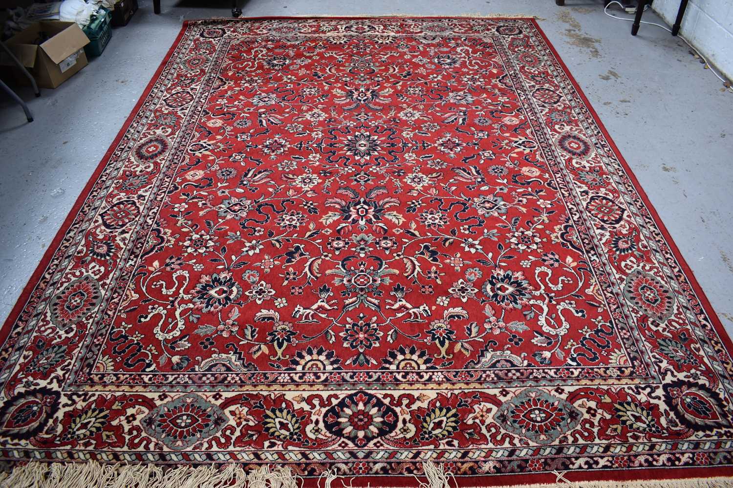 A large Middle Eastern wool rug with red ground, the centre decorated with stylised flowers with