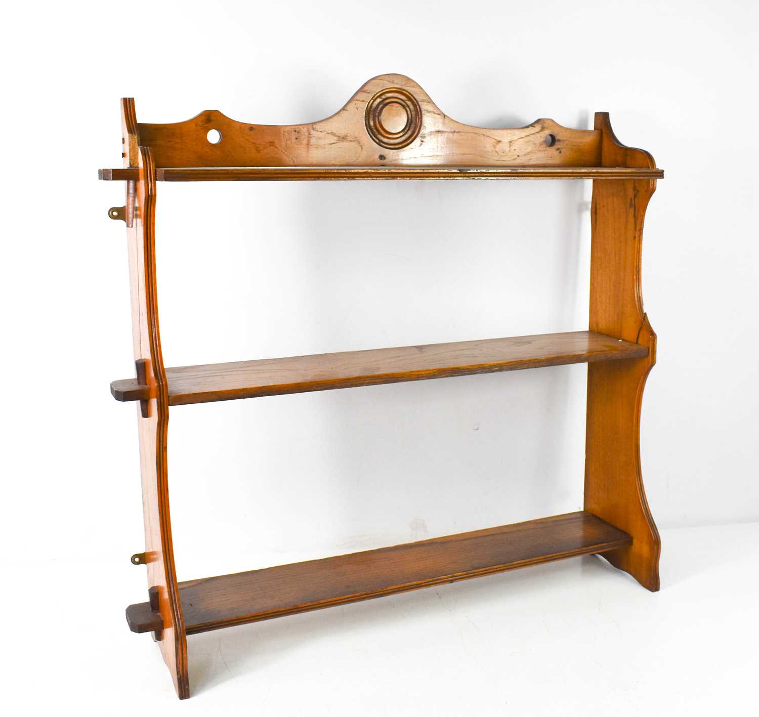 A 19th century fruitwood wall shelf, composed of a shaped and roundel carved top rail and two shaped