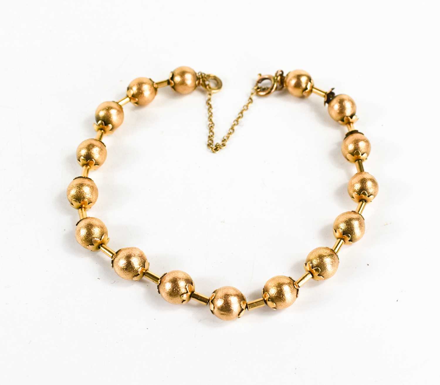 A Victorian gold bracelet of ball and bar form, each ball textured with flower finial to either end,
