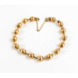A Victorian gold bracelet of ball and bar form, each ball textured with flower finial to either end,