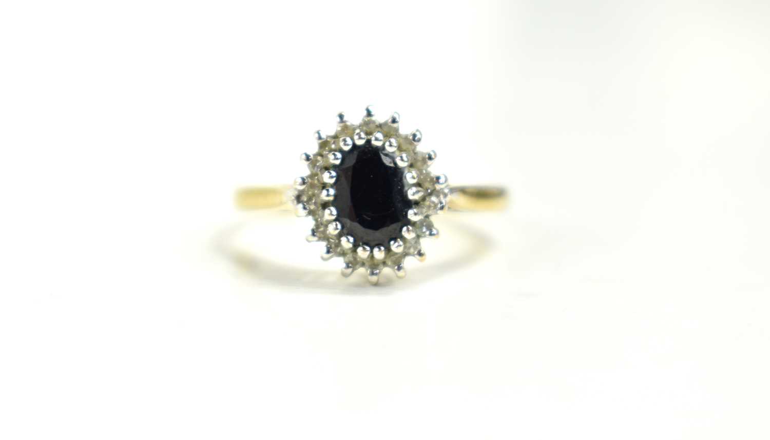 A 9ct gold sapphire and diamond cluster ring, the oval sapphire of approximately 6.2 by 4.2mm,