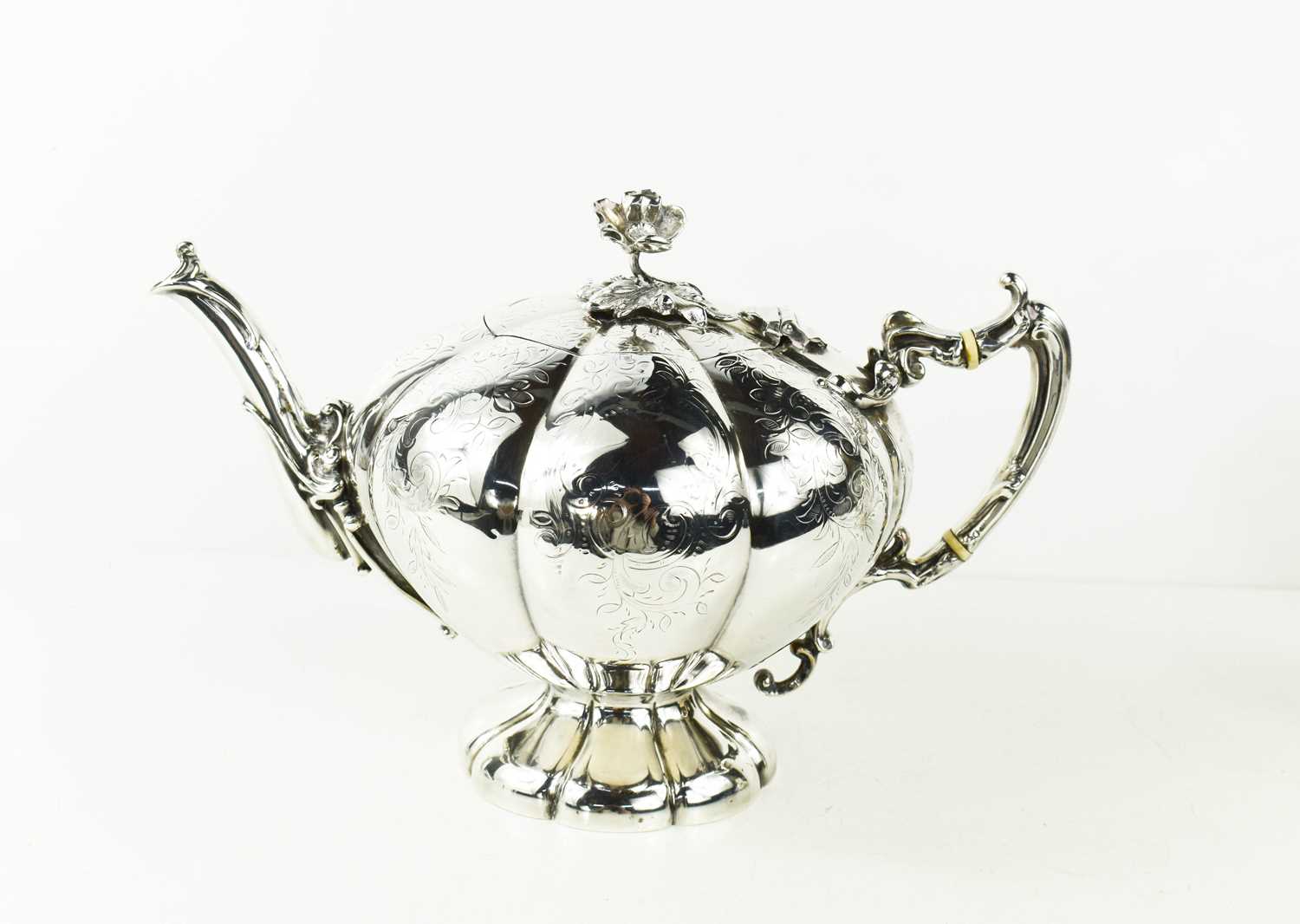 A 19th century white metal tea pot, of peach form, engraved with scrolling foliage, the lid having a