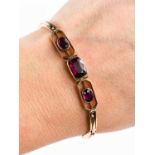 A 9ct rose gold bracelet set with three amethysts, the central emerald cut amethyst of approximately
