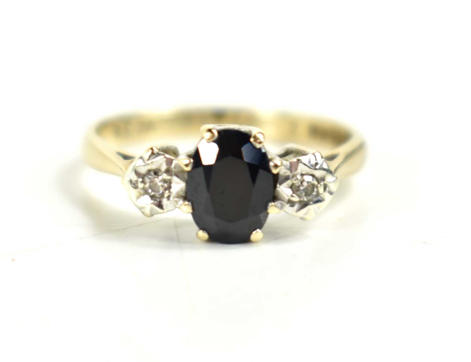 A 9ct gold, sapphire and diamond ring, the central oval cut sapphire of approximately 6.8 by 5.5mm