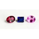 A group of loose synthetic gemstones: emerald cut blue sapphire, oval cut pink sapphire and oval cut