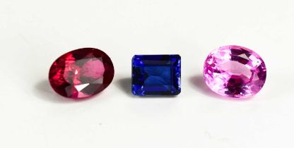 A group of loose synthetic gemstones: emerald cut blue sapphire, oval cut pink sapphire and oval cut