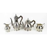 A silver tea set, embossed with Rococo style scrollwork, comprising tea pot, water pot, sugar