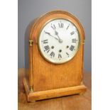 A 19th century oak mantle clock, with arched top and Roman numeral dial, striking chimes, 34 by 25
