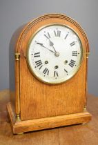 A 19th century oak mantle clock, with arched top and Roman numeral dial, striking chimes, 34 by 25